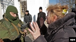 Crimea-- A Ukrainian woman speaks with an armed man in military uniform, believed to be Russian soldiers, block the Ukrainian navy base in Novoozerniy village, March 3, 2014