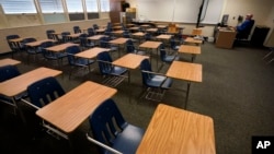 FILE - Math teacher Doug Walters sits among empty desks as he takes part in a video conference with other teachers to prepare for at-home learning at Twentynine Palms Junior High School in Twentynine Palms, Calif., Aug. 18, 2020. (AP Photo/Gregory Bull, File)