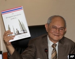 FILE - Chairman of the Constitution Drafting Commission Meechai Ruchupan holds the draft of new constitution during a press conference at the Parliament in Bangkok, Thailand, March 29, 2016.
