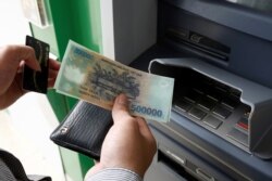 FILE - A man withdraws money from an ATM at a branch of Vietnam Prosperity Joint Stock Commercial Bank (VPBank) in Hanoi, Nov. 15, 2017.