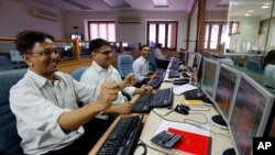 FILE - Indian stockbrokers celebrate as they watch the Bombay Stock Exchange (BSE) index on their trading terminal in Mumbai, India.