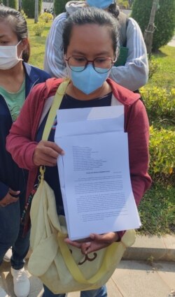 អ្នកស្រី​ អ៊ុក សុភ័ក្រម៉ូលីកា បង្ហាញ​ញត្តិ​ ដែល​ក្រុម​អតីត​បុគ្គលិក​នយោជិត​ក្រុមហ៊ុន​ណាហ្គាវើលដ៍​គ្រោងយក​ទៅ​កាន់​ស្ថានទូត​បរទេស​មួយ​ចំនួន​ ក្នុង​រាជធានី​ភ្នំពេញ កាល​ពី​ថ្ងៃ​ច័ន្ទ ទី១៧ ខែ​មករា ឆ្នាំ​២០២២។ (ណឹម សុភ័ក្រ្តបញ្ញា/វីអូអេ)