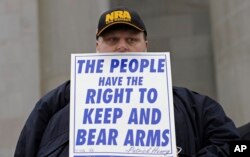 FILE - John Doll, of Renton, Wash., holds a sign that reads "The people have the right to keep and bear arms" during a gun rights rally at the Capitol in Olympia, Wash.