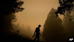 산불이 확산하고 있는 미 서부 오리건주 에스타카다에서 11일 한 남성이 물통을 들고 불에탄 집을 돌아보고 있다.