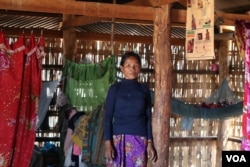 អ្នកស្រី ល្មាម ផ្ចាញ ជនជាតិដើម​ភាគតិច​កាចក ឈរ​នៅក្នុង​ផ្ទះ​របស់​អ្នកស្រី ដែល​មាន​គ្នា​រស់នៅ​១០នាក់។ (ស៊ុន ណារិន/VOA)