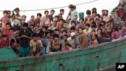 Migrants sit on their boat as they wait to be rescued by Acehnese fishermen on the sea off East Aceh, Indonesia, Wednesday, May 20, 2015. (AP Photo/S. Yulinnas)
