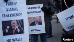 Protesters hold signs during a demonstration against U.S. President Donald Trump on Presidents' Day in Union Square, New York, U.S., February 18, 2019. 