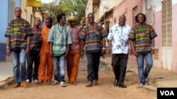 The eight members of Super Mama Djombo, including founder Ze Manel Fortes and composer Atchutchi, walk through the streets of Bissau's old town, Guinea-Bissau, May 2, 2012. (K. Thomas/VOA)
