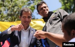 Venezuelan opposition leader Juan Guaido, left, pumps fists with a supporter as fellow opposition leader Leopoldo Lopez looks on in Caracas, April 30, 2019.