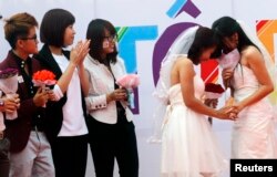 FILE - Newly married same-sex couple Tran Ngoc Diem Hang (R) and Le Thuy Linh (2nd R) share a moment during their public wedding as part of a lesbian, gay, bisexual, and transgender (LGBT) event on a street in Hanoi, October 27, 2013.