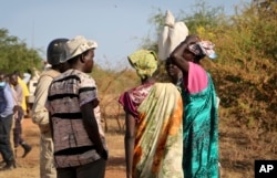 FILE - Women and girls speak to members of a U.N. peacekeeping patrol as they walk to get food in Bentiu, fearful of being attacked on the way, near Nhialdu, South Sudan, Dec. 7, 2018.