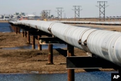 FILE - In this 2007 file photo, an oil transit pipeline runs across the tundra to flow station at the Prudhoe Bay oil field on Alaska's North Slope.