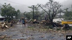 FILE - People walk through debris in Samoa's capital Apia, Dec. 14, 2012, after cyclone Evan ripped through the South Pacific island nation. 