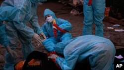 Relatives in personal protective equipment weep over the body of a person who died of COVID-19 before cremation in Gauhati, India, Sept. 28, 2020.