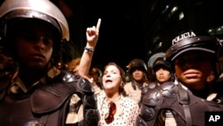 Mitzy Capriles de Ledezma chants for the release of her husband, Mayor Antonio Ledezma, as national police officers guard intelligence service police headquarters in Caracas, Venezuela, Feb. 19, 2015. 