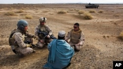 Dua marinir AS ditemani seorang penerjemah Afghan berbincang dengan seorang warga Afghanistan di Provinsi Helmand, Afghanistan, 11 Desember 2009. (Foto: AP)