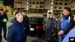 In this photo taken from video released by Russian TV Pool on Sunday, March 19, 2023, Russian President Vladimir Putin talks with local residents during his visit to Mariupol in Russian-controlled Donetsk region, Ukraine.