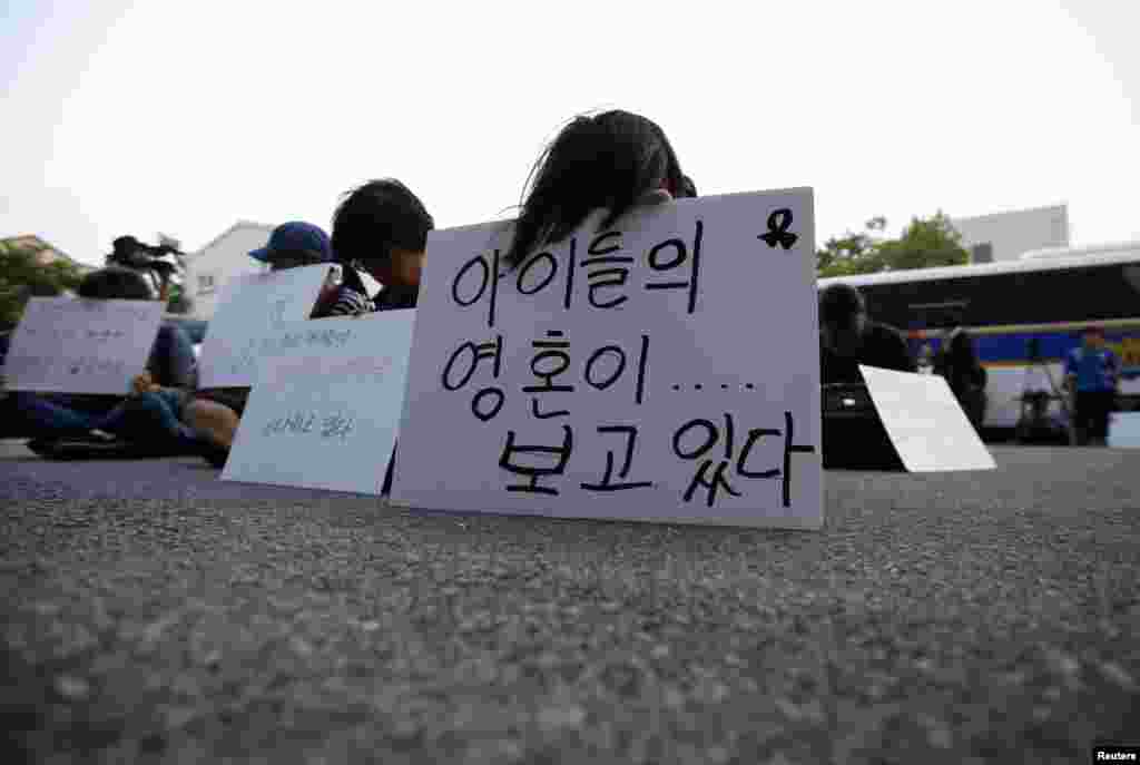 Family members of victims onboard sunken ferry Sewol sit in front of a building in which crew members are detained, after attending a hearing at the local court in Gwangju, South Korea, June 10, 2014.