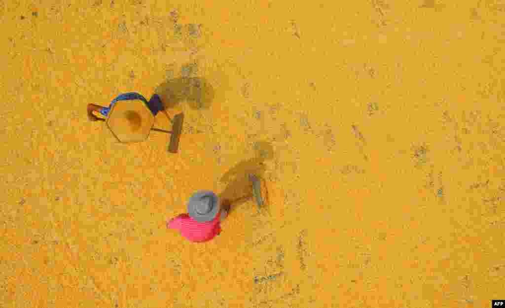 中国山东省临沂市郯城县，2018年8月30日，两位农民在收获季节晒玉米。中国玉米不能自给自足，需要进口。对美国玉米增加关税会抬高中国市场上的玉米价格，而不少玉米用于猪饲料，所以也会抬高猪肉价格。由美国国会成立的美中经济与安全审查委员会的报告说，在中美贸易战阴霾下，6月份美国对中国农产品出口与去年同比下跌34.4%。