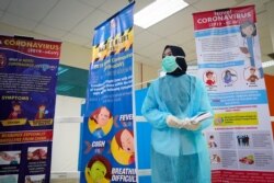 A health official wearing a protection suit and a face mask waits for passengers at a cruise ship terminal in Port Klang, Malaysia, Feb. 13, 2020.