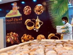 Seorang penjual mengenakan masker saat memegang sekotak kurma di tokonya, di tengah pandemi COVID-19, menjelang bulan suci Ramadan, di Riyadh, Arab Saudi 20 April 2020. (Foto: dok).