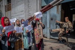Seorang anggotaTaliban menyaksikan para perempuan Afghanistan saat demonstrasi untuk menuntut lebih banyak hak bagi perempuan, di depan bekas Kementerian Urusan Perempuan di Kabul, Afghanistan, 19 September 2021. (Foto: AFP)