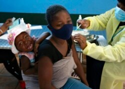 جوہانسبرگ میں ایک خاتون اپنے بچے کو ویکسین لگوا رہی ہے۔ افریقہ میں ویکسین لگانے کی شرح صرف 7 فی صد ہے۔