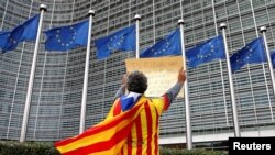 FILE - Catalan Raimon Castellvi wears a flag with an Estelada (Catalan separatist flag) as he protests outside the European Commission in Brussels after Sunday's independence referendum in Catalonia, Belgium, Oct. 2, 2017.