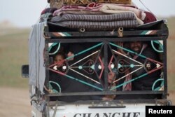 FILE - People ride in a vehicle stacked with their belongings after fleeing clashes in the northern Syrian town of al-Bab, Syria, Jan. 26, 2017.