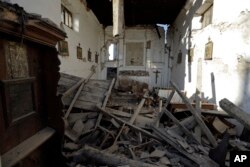 Paintings hang on the walls of the earthquake-damaged church in the village of Santi Lorenzo e Flaviano, central Italy, Aug. 27, 2016.