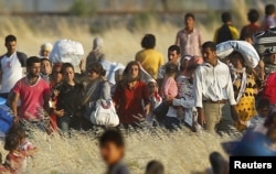 Syrian Kurds from Kobani walk to the border fences as seen from the Turkish border town of Suruc in Sanliurfa province, Turkey, June 26, 2015.