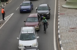 The Ivorian environmental activist Andy Costa also known as the cycling ambassador in Africa, pedals his bike among cars in a street of the central business district of Plateau in Abidjan, Ivory Coast September 4, 2020. Picture taken September 4, 2020. REUTERS/Luc Gnago