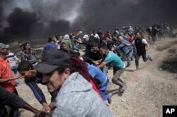 Palestinian protesters chant slogans as they pull part of the fence that the Israeli Army placed, during a protest at the Gaza Strip's border with Israel, April 13, 2018.