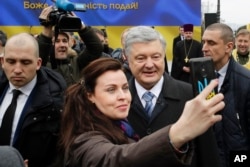 Incumbent Ukrainian President Petro Poroshenko, surrounded by bodyguards, poses for a selfie with a supporter, after a public prayer service ahead of Sunday's presidential election, in Kyiv, Ukraine, March 30, 2019.