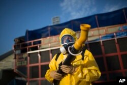 FILE - A health worker stands in the Sambadrome as he sprays insecticide to combat the Aedes aegypti mosquitoes that transmit the Zika virus, in Rio de Janeiro, Brazil, Jan. 26, 2016.