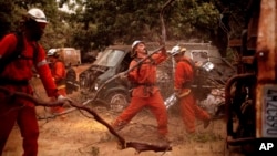 Inmate firefighters clear brush to create a fire break while battling the Ferguson Fire in unincorporated Mariposa County, Calif, on Monday, July 16, 2018.