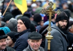 A man holds an Orthodox cross as people support an independent Ukrainian church near the St. Sophia Cathedral in Kyiv, Ukraine, Dec. 15, 2018.