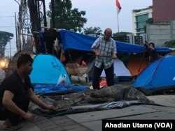 Saat pagi tiba para pengungsi dari Afghanistan melipat tenda yang dijadikan tempat tidurnya di depan rumah detensi imigrasi Jakarta .
