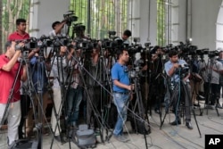 FILE - Bangladeshi journalists cover proceedings outside a court in Dhaka, Bangladesh on May 3, 2016.