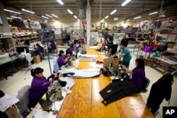FILE - Workers manufacture car dash mats at a maquiladora belonging to the TECMA group in Ciudad Juarez, Mexico, Dec. 27, 2013.