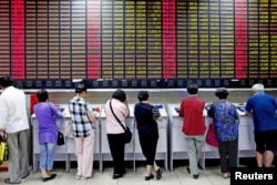 Investors look at computer screens showing stock information at a brokerage house in Shanghai, China, July 8, 2015.