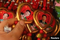 A woman picks a souvenir necklace with a portrait of Chinese President Xi Jinping from a selection that also includes necklaces featuring late Chinese Chairman Mao Zedong at a stall in Tiananmen Square in Beijing, China, February 26, 2018.
