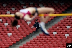 FILE – Observed by a security guard, a Russian athlete attempts the women’s high jump during the IAAF World Challenge Beijing at China’s National Stadium, May 21, 2014. The World Anti-Doping Agency has accused Russians of participating in a vast doping scheme.