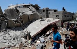 People inspect the rubble of a destroyed residential building which was hit by Israeli airstrikes, in Gaza City, Wednesday, May 12, 2021. (AP Photo/Adel Hana)