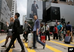 FILE - Mainland Chinese tourists carry suitcases as they walk at a shopping district in Hong Kong, April 12, 2015.