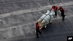 FILE - U.S. Navy sailors push ammunition across the deck of the U.S.S. Dwight D. Eisenhower aircraft carrier, Nov. 21, 2016, as the ship carries out military operations against IS extremists in Syria and Iraq.