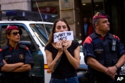 A woman protests holding a sign next to Mossos d'Esquadra police officers, in Barcelona, Spain, Sept. 20, 2017.