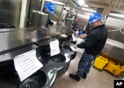 FILE - A crew member looks over maintenance records in the shower area during a tour of the nuclear-powered aircraft carrier USS Gerald R. Ford at Newport News Shipbuilding in Newport News, Virginia, April 14, 2016.