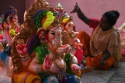 Seorang pengrajin mendekorasi patung dewa Hindu berkepala gajah Lord Ganesha menjelang festival Ganesh Chaturthi di New Delhi, 14 Agustus 2021. (Foto: Sajjad HUSSAIN / AFP)