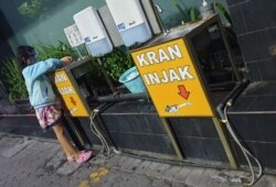 Seorang anak memakai masker dan faceshield sedang mencuci tangan di wastafel, di pusat penjualan elektronik di Surabaya (foto Petrus Riski-VOA).